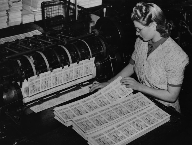 6th February 1939:  A young woman checks tickets for the FA Cup Final as they come off the press.  (Photo by Fox Photos/Getty Images)